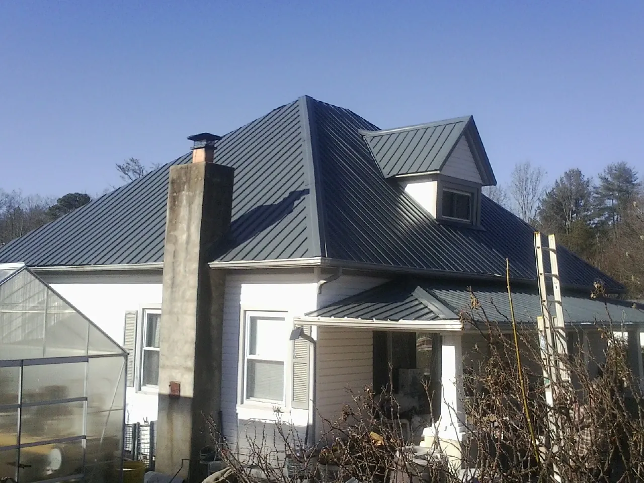 Dark blue standing seam metal roof on a white farmhouse with dormer — Slate & Tile Roof Repair by Roofing Brothers in Valparaiso