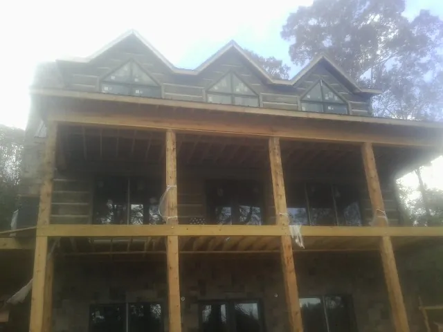 Dormers and porch framing on a large log home under construction — Roof Coating work by our crew in Valparaiso