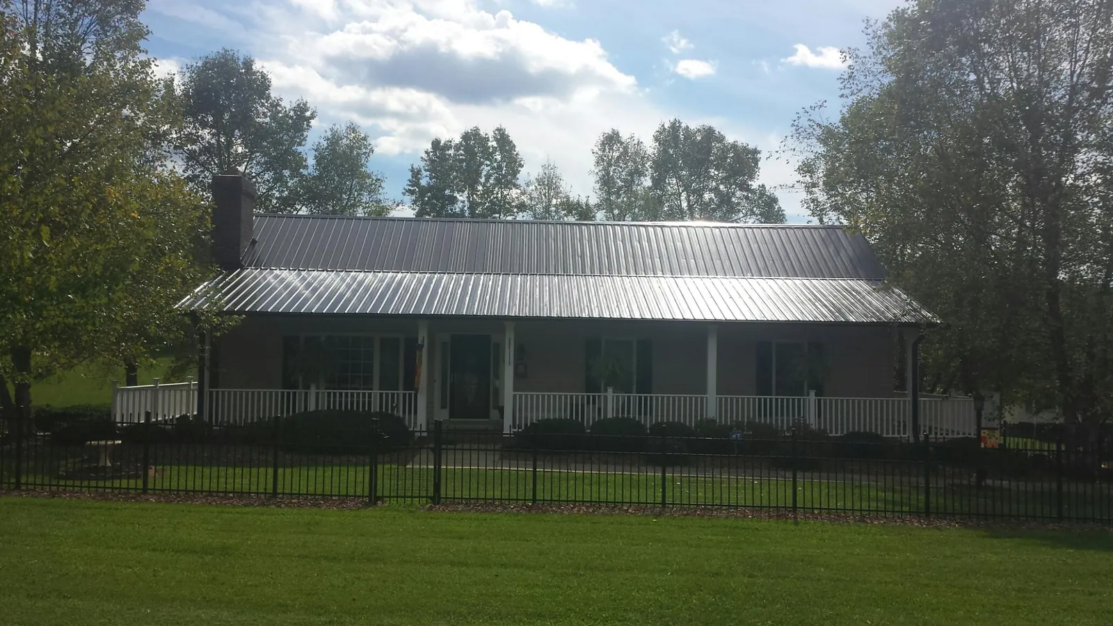 Gray metal roof on a brick ranch with a full width front porch — Gutter Guard Installation work by our crew in Valparaiso
