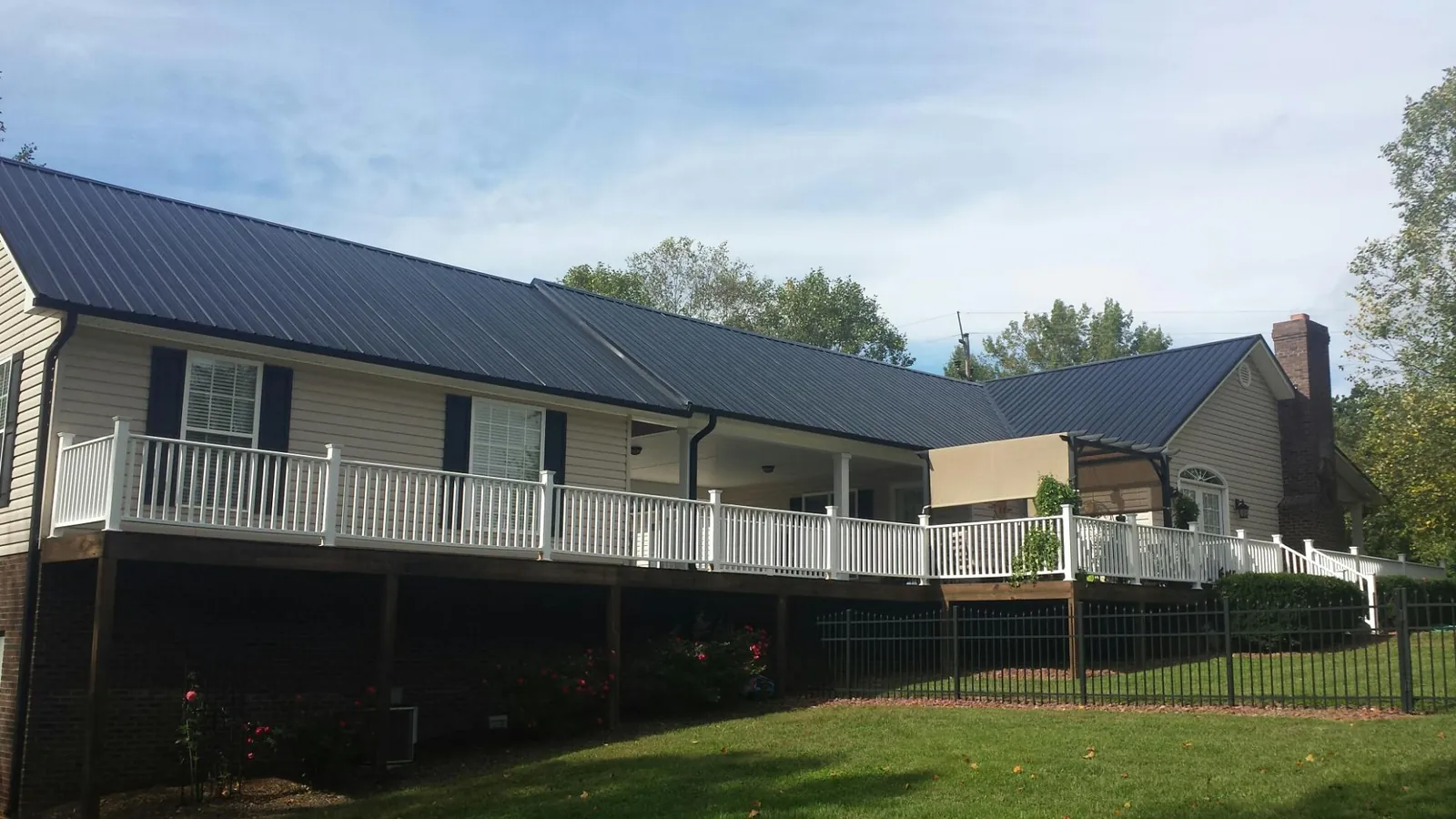 Black metal roof above a long white railed deck on a hillside home in Valparaiso