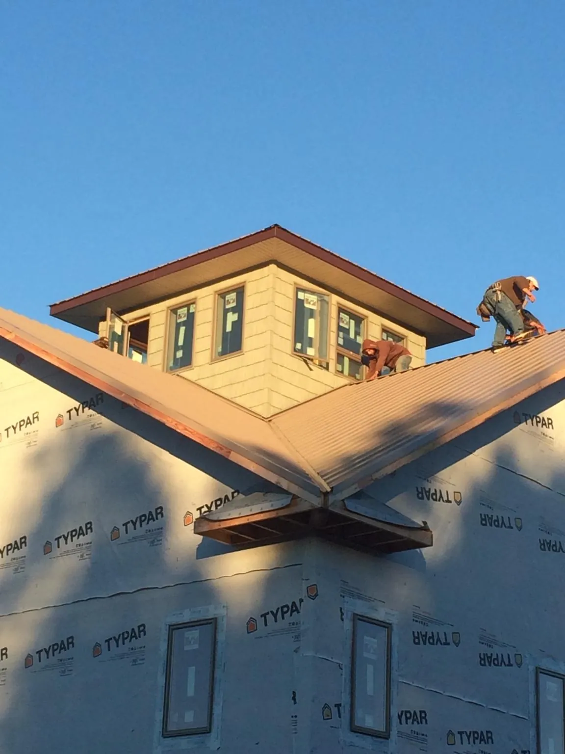 Roofers working around a rooftop cupola on a new metal roof at sunset — Roof Waterproofing in Valparaiso by Roofing Brothers